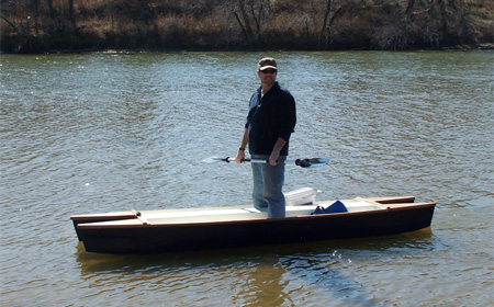 John standing in the wooden twin hull fishing kayak he created